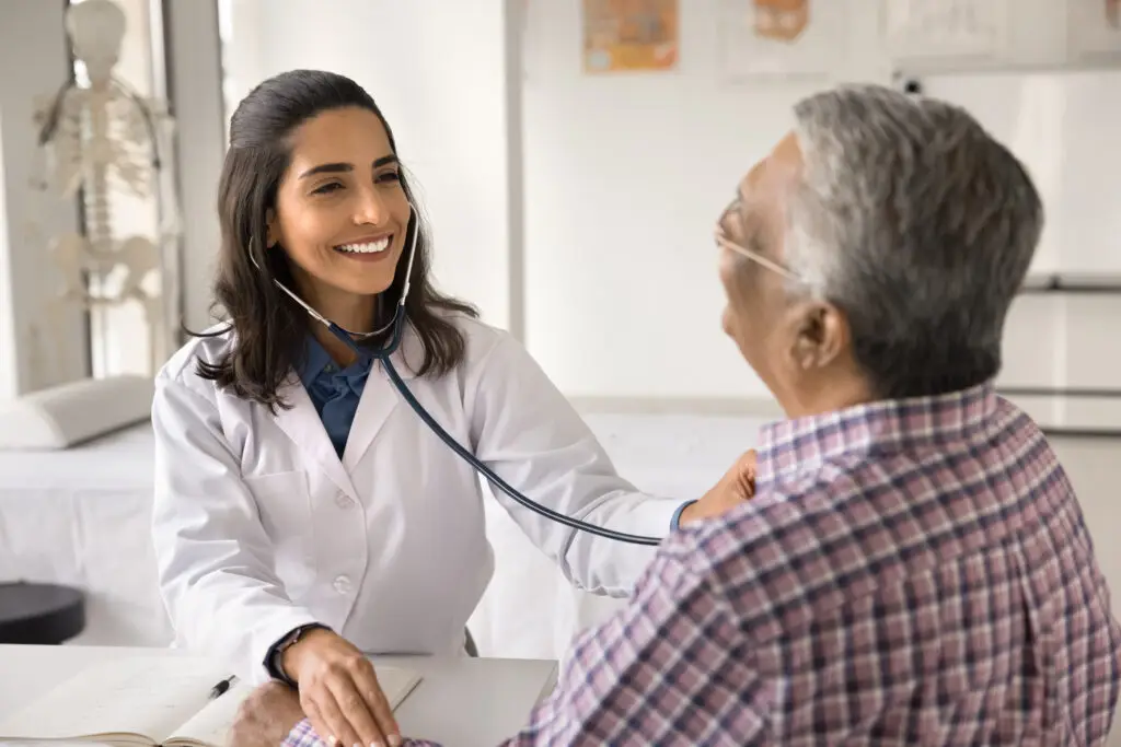 Female doctor check pulse listen to heart of aged patient